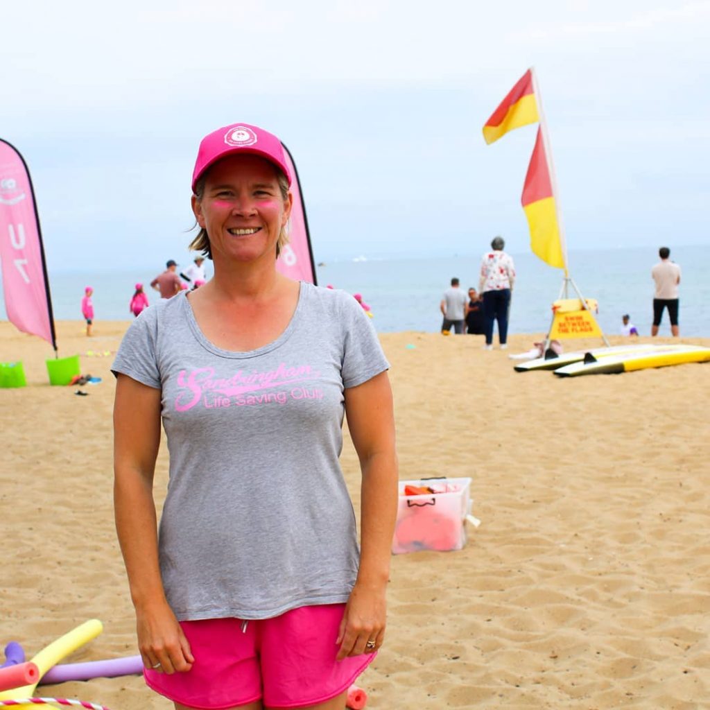 White woman stands in front of flags and nippers set up.