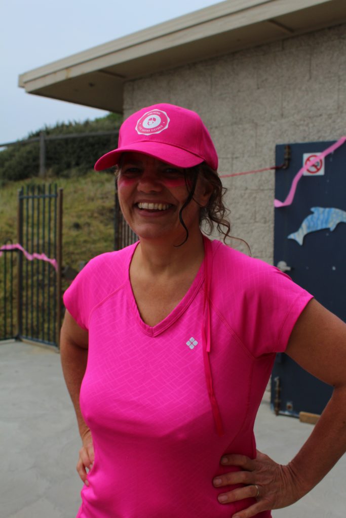 Woman dressed in pink smiling on the club's balcony.