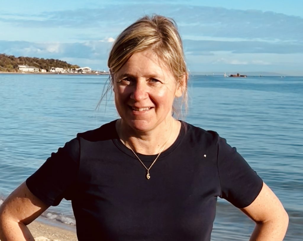 White woman smiles at the beach.